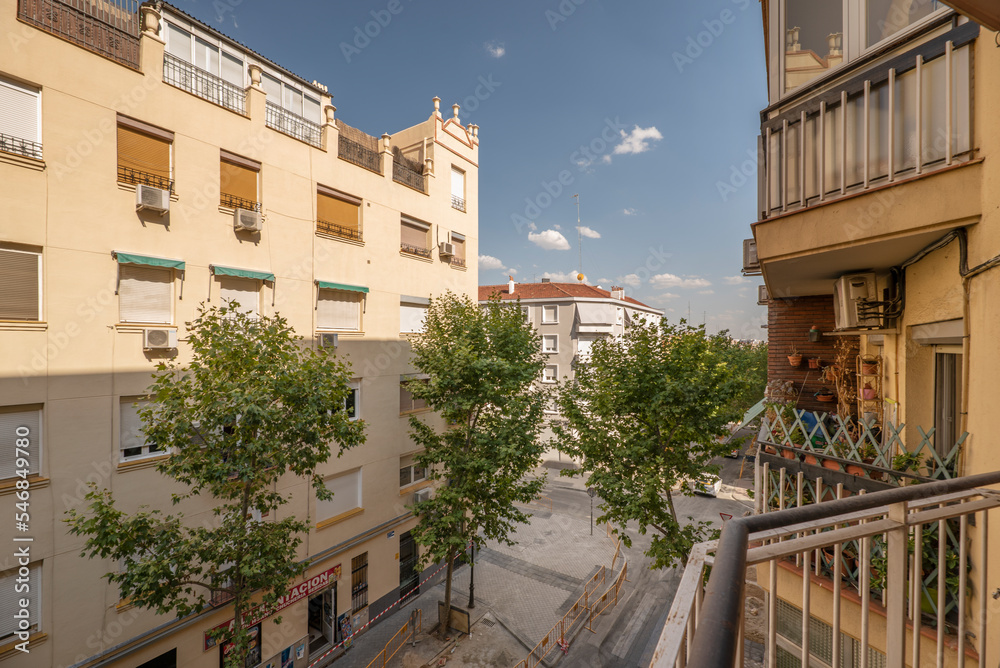 Views of a street with young trees, balconies with plants and skies with clouds and clear