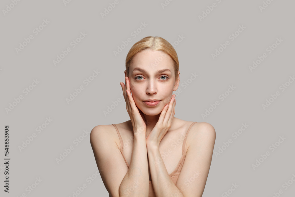 Close up portrait of pretty nice lovely lady with naked shoulders touching her face by hands on white background Close up portrait of pretty nice lovely lady with naked shoulders touching her face by hands on white background