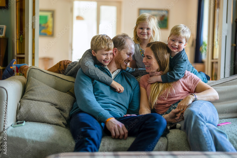 Happy young family sitting on sofa at home
Happy young family sitting on sofa at home