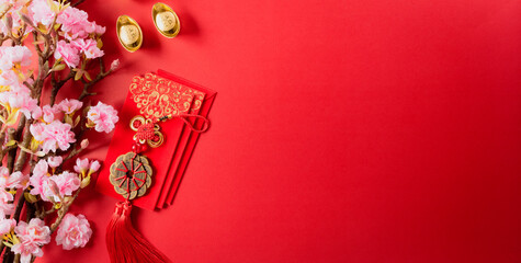 Chinese new year decorations made from red packet, orange and gold ingots or golden lump on a red background. Chinese characters FU in the article refer to fortune good luck, wealth, money flow.