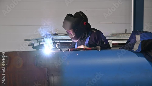 Factory Worker Grinds Metal Construction using angle grinder. Bright Golden Sparks comes out, Heavy Manual Work at Modern Steel Making Industry. Slow Motion.