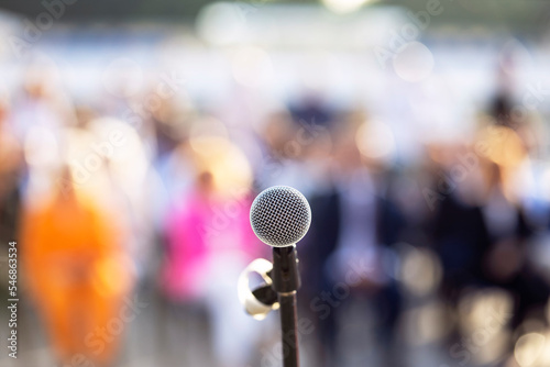 Microphone in the focus, blurred people in the background. Public speaking concept. © wellphoto