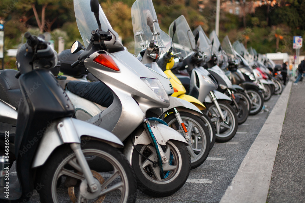 many scooters and motorcycles are parked in a long row.