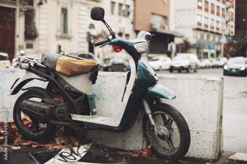 an old motorcycle, rusty and broken, abandoned in the middle of the city.