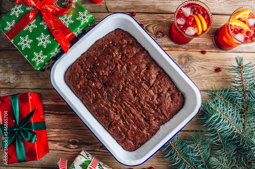 Christmas brownies with walnut and cranberry on rustic wooden background. Fir tree branches and Christmas decorations.