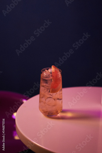 cocktail with alcohol with orange and ice in a tall glass on a white table