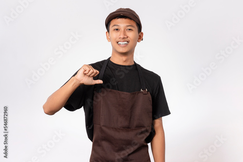 Handsome barista asian man wearing brown apron and black t-shirt isolated over white background pointing yourself with fingers