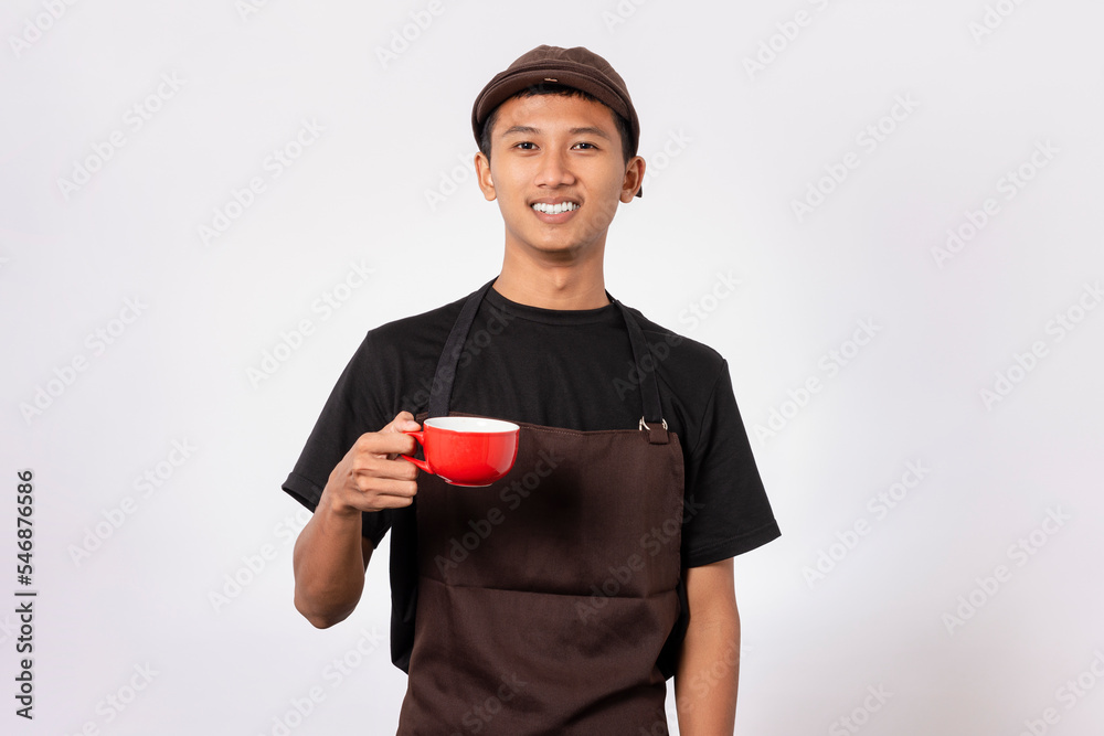 Handsome barista asian man wearing brown apron and black t-shirt isolated over white background. Barista holding coffee cup, serving coffee to customer Handsome barista asian man wearing brown apron and black t-shirt isolated over white background. Barista holding coffee cup, serving coffee to customer