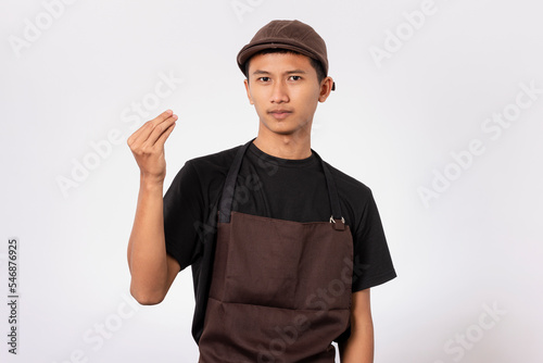 handsome barista asian man wearing brown apron and black t-shirt isolated over white background. Barista doing Italian gesture with hand and fingers. arguing concept.