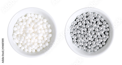 White and silver colored sugar pearls for decorating, in white bowls. Edible dragees and decorative balls, also known as love pearls, with a diameter of four mm, used as a topping for sweet treats.  photo