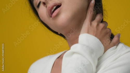 Close up studio yellow background Indian sad ethnic woman girl lady female suffer pain ache in neck rubbing muscle tension cervical osteochondral problem tired bad posture trouble sick trauma damage photo