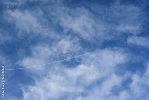 the plane is flying in a blue sky with clouds