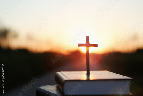 Fototapet Bright sun light and bible book and the cross silhouette of the Holy Jesus Chris