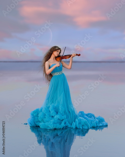 A girl plays the violin in the middle of a pink lake photo
