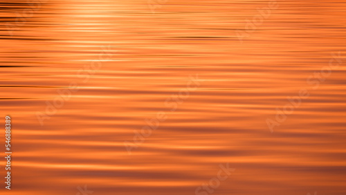 Abstract colorful motion blur background of ripples on sea surface with beautiful golden sunlight reflection at morning time