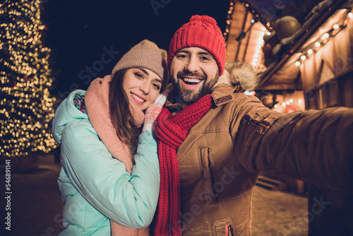 Photo of positive pretty girlfriend boyfriend tacking selfie cuddling walking outdoors urban city market