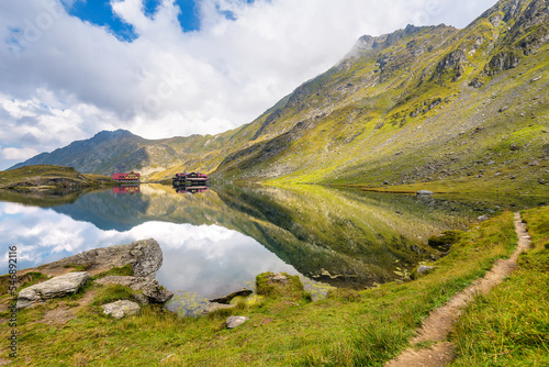 Scenic view of Transylvanian Alps mirrored to high altitude Balea lake in Romania against dramatic stormy clouds