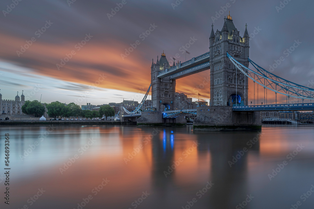 Tower bridge at sunrise.  The sunrise is making the clouds overhead red. Long exposure to smooth out the water