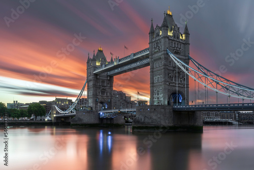 Tower bridge at sunrise.  The sunrise is making the clouds overhead red. Long exposure to smooth out the water