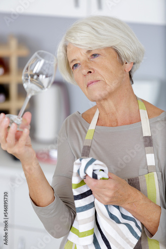 mature smiling housewife cleaning wine glasses