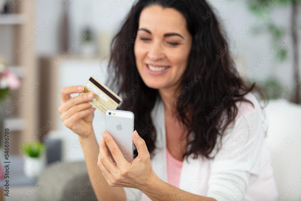 mature woman holding credit card while talking on mobile phone mature woman holding credit card while talking on mobile phone