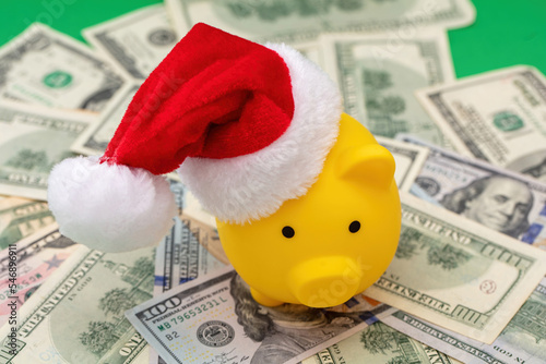 Christmas holiday bonus and expenses. Piggy bank with Santa hat on US dollars money photo