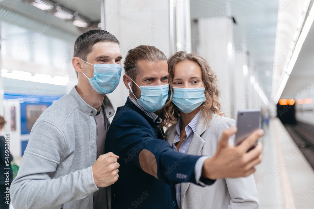 Fototapeta premium group of passengers in protective masks taking selfies in the subway.