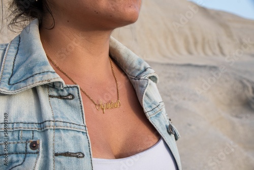 Closeup of a Hispanic woman wearing a gold name necklace. photo