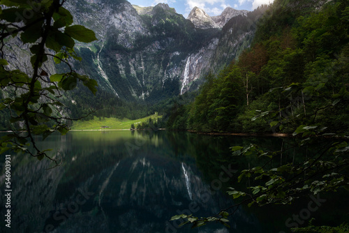 View of the lake Obersee in the forest with Röthbach Waterfall falling from the mountain in the background. Germany. Summer. German Alps. Tranquillity.