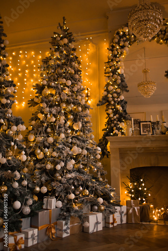 warm and cozy evening in Christmas room interior design,Xmas tree decorated by lights presents gifts,toys, deer,candles, lanterns, garland lighting indoors fireplace.holiday living room.magic New year
