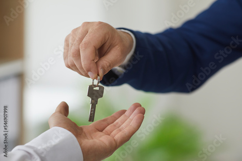 Welcome to new house. Man takes keys from real estate agent after signing lease or purchase agreement. Close up of hand of male real estate agent handing over key to new owner of apartment.