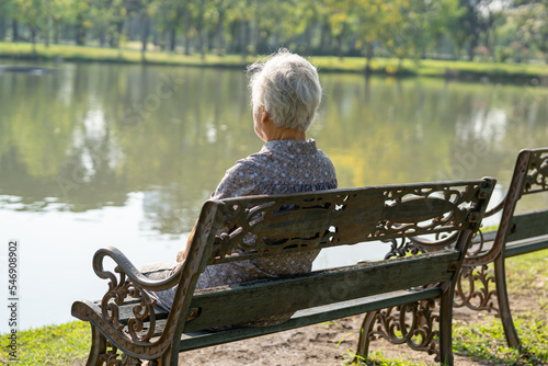 Obraz na płótnie Asian elderly woman depressed and sad sitting back on bench in autumn park