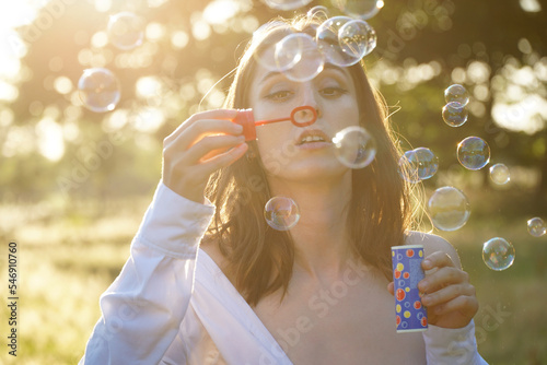 Beautiful woman blowing soap bubbles in a field on a beautiful summer day 