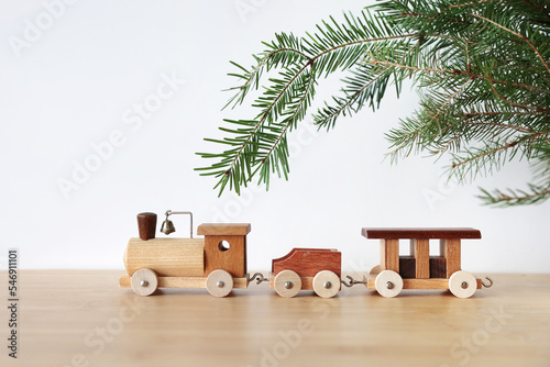 Wooden toy train on wooden table with fir branch christmas postcard eco toys