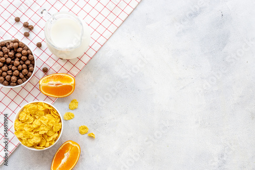 Bowls of corn flakes with milk and oranges for breakfast
