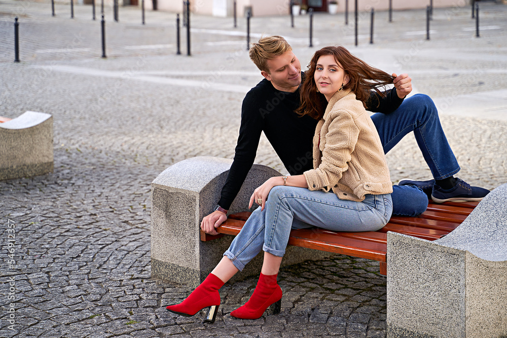 Beautiful young couple sitting on a bench in the city during a romantic date