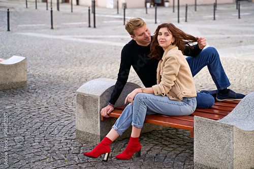 Obraz na płótnie Beautiful young couple sitting on a bench in the city during a romantic date w salonie