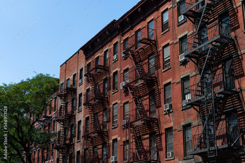 Row of Old Red Brick Apartment Buildings in Hell's Kitchen of New York City with Fire Escapes