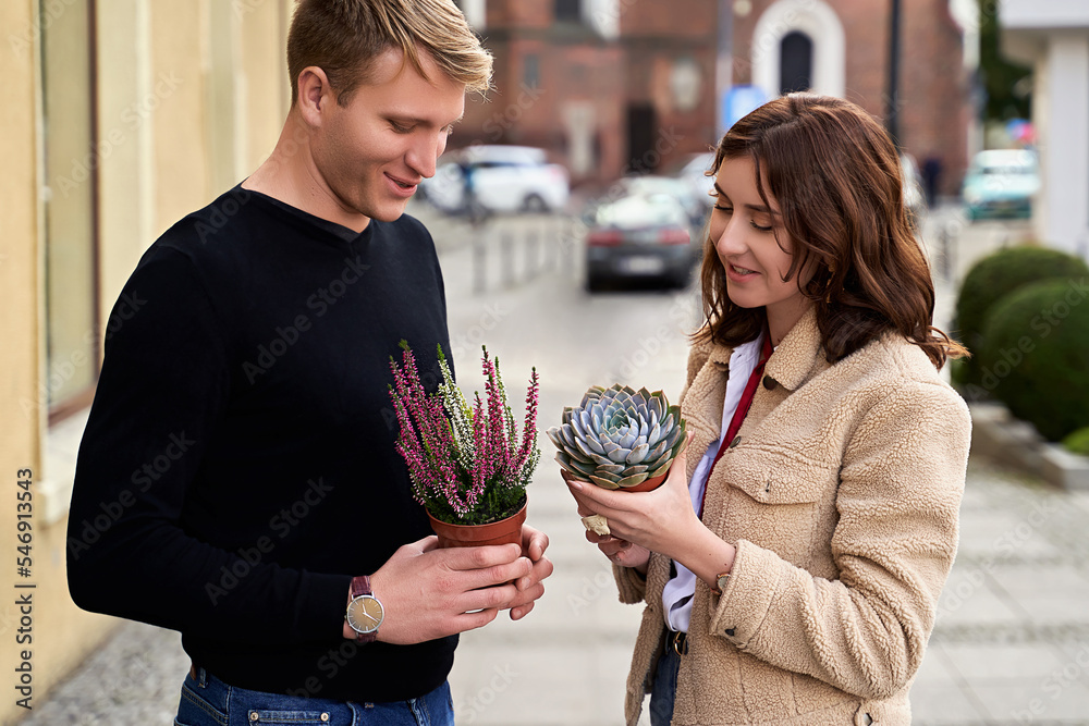Man and woman holding a purple sempervivum succulent plant and blooming violet heather plant