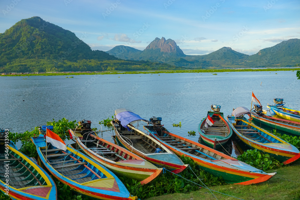 Fishing boats anchored on the banks of the Jatiluhur reservoir. Beautiful view with mountains in the background.