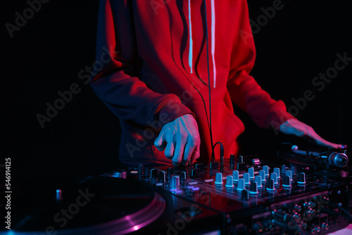 Hip hop dj scratches vinyl record on turntable. Disc jockey mixing musical tracks on turntables on party in night club