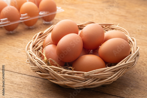 Heap of Chicken eggs on wicker basket on wooden plate background