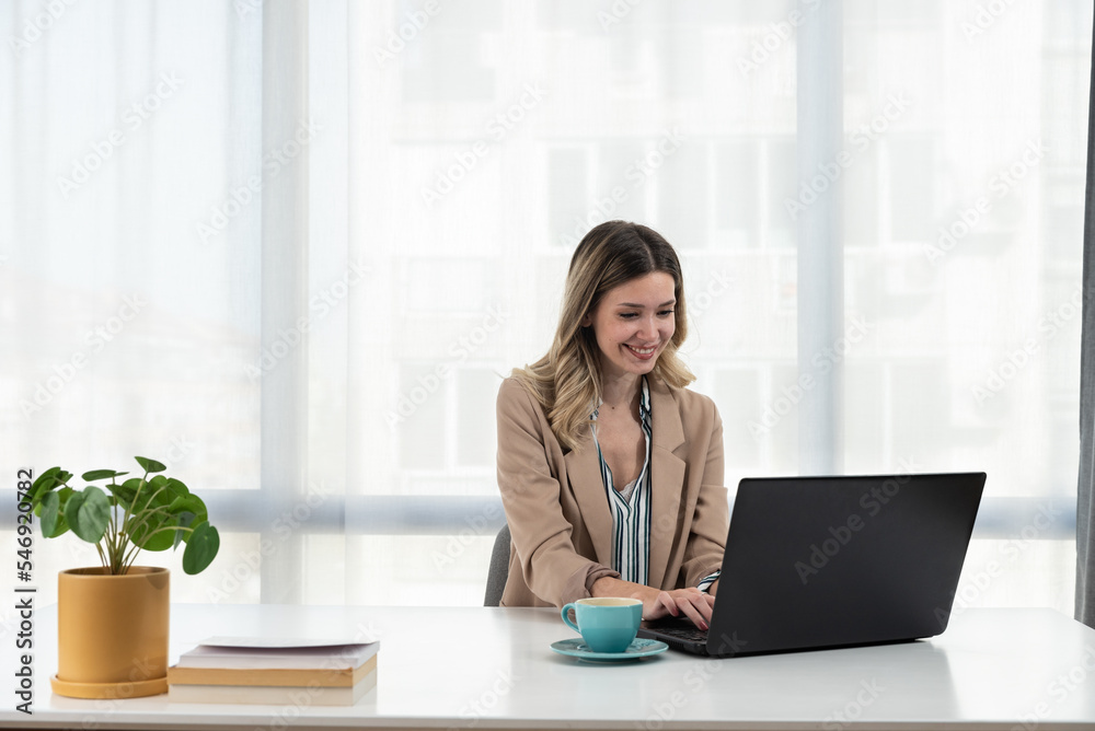 Happy young business woman in formal wear entrepreneur using computer looking at screen working on internet sit at office desk, smiling female professional employee typing email on laptop at workplace Happy young business woman in formal wear entrepreneur using computer looking at screen working on internet sit at office desk, smiling female professional employee typing email on laptop at workplace