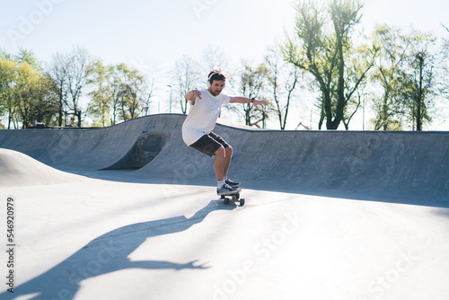 Man riding skateboard on ramp at skate park with arms outstretched