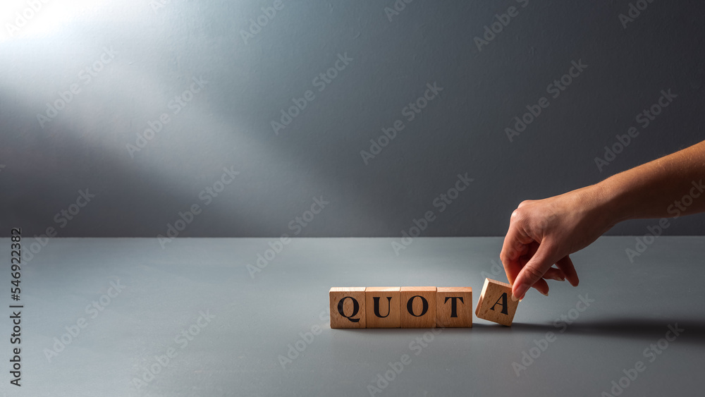 womans hand posing wooden block with the word quota . cocept of work Quota's .equality. - obrazy, fototapety, plakaty 