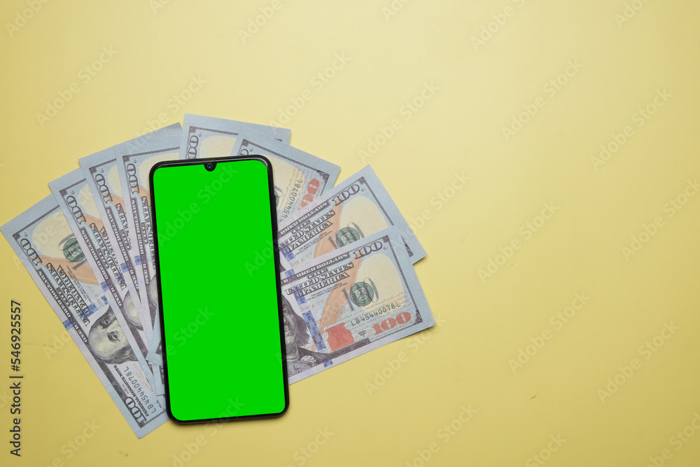A picture of green chroma key smartphone on top of fake money. A picture of green chroma key smartphone on top of fake money.