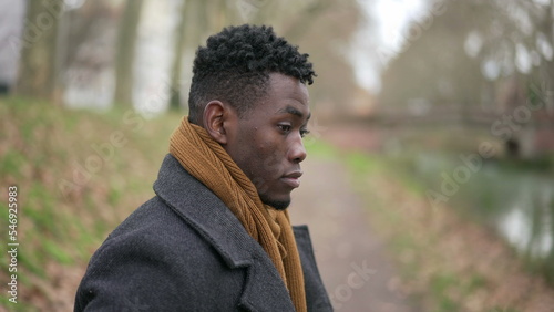 Contemplative young black man standing outside in nature park