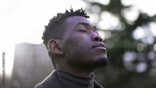 Contemplative black man looking at sky with HOPE and FAITH, closing and opening eyes