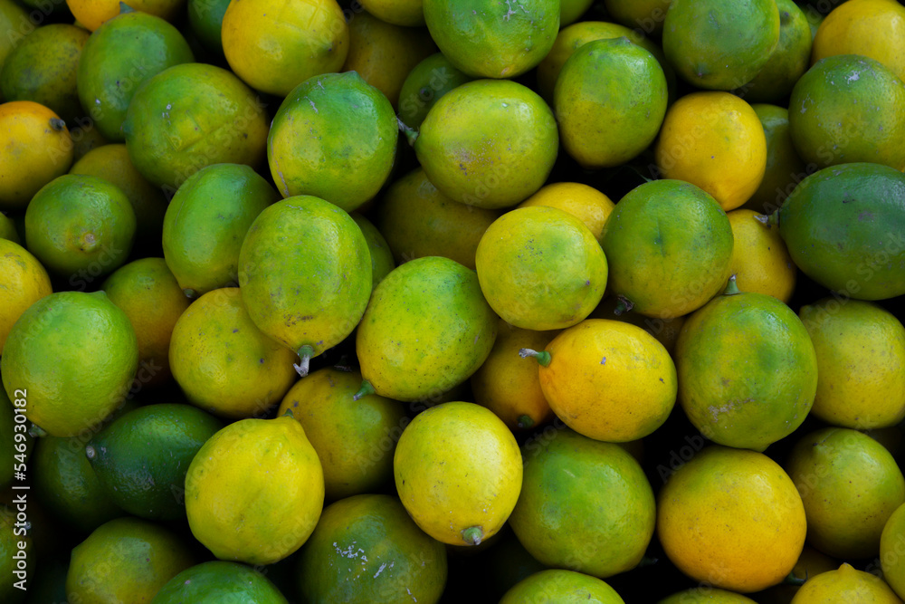 Background from citrus fruits. Yellow and green lemons in tray. Fruits in greengrocer's shop at a Georgian street market. The concept of buying farm products. Small business support. Vegan fruit. Food