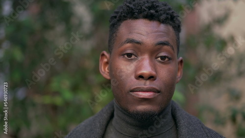Confident young black man standing outside staring camera portrait face close-up